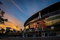 the sun is setting behind an arena building