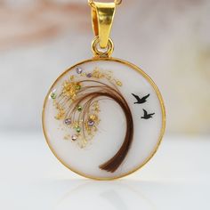 a white and gold pendant with birds flying around it