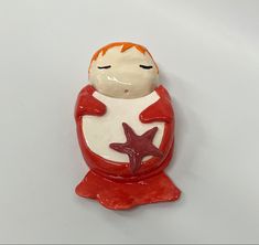 a red and white ceramic figurine with a star on it's chest