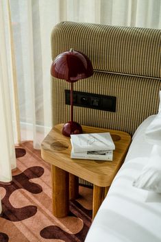 a small wooden table with a book on it next to a couch in a hotel room