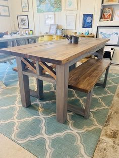 a wooden table sitting on top of a blue rug next to a wall with pictures