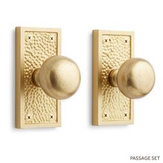 two brass door knobs on the side of a white wall, one has a ball and