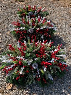 a small christmas tree with red berries and pine cones on it's branches in the gravel