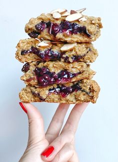 a person holding up a stack of cookies with blueberries and almonds