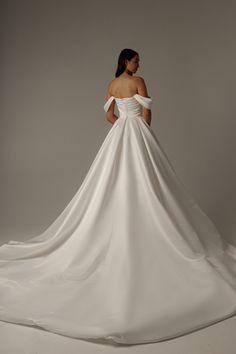 a woman in a white wedding dress with her back to the camera, looking down