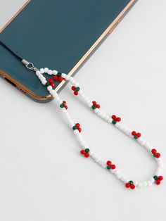 a white beaded necklace with red, green and white beads hanging from it's side