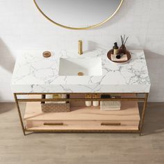 a bathroom vanity with marble counter top and gold frame around it, along with a round mirror above the sink