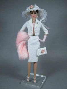 a barbie doll wearing a white dress and pink fur stoler with matching purses