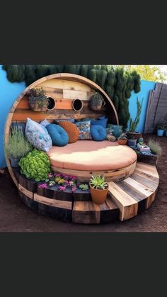 a circular bed made out of wooden pallets in the middle of a yard with succulents and plants