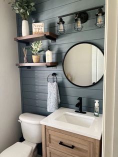 a white toilet sitting next to a sink in a bathroom under a mirror and shelves