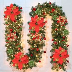 two christmas wreaths decorated with poinsettia and pine cones are hanging on the wall