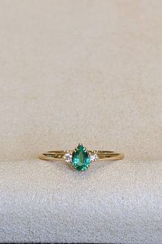 Elevate your style with our stunning 18K yellow gold Three Stone Ring, featuring a captivating 0.30 Ct. emerald flanked by radiant diamonds. This modern design embodies the essence of glamour and sophistication, setting new trends in jewelry fashion. Whether it's a gift for a special someone or a self-indulgent treat, this non-traditional gemstone ring is a symbol of elegance and refinement. Embrace the beauty of custom jewelry and make a statement with this exquisite piece that transcends traditional norms. Elegant Proposal Emerald Ring With Brilliant Cut, Elegant 14k Gold Emerald Ring For Proposal, Classic Emerald Diamond Promise Ring, Classic White Gold Emerald Ring For Proposal, Elegant Yellow Gold Emerald Ring For Proposal, Elegant Emerald Cut Proposal Ring, Elegant Birthstone Ring With Prong Setting For Proposal, Fine Jewelry Pear-shaped Emerald Ring Vvs Clarity, Elegant 14k Gold Ring With Timeless Design