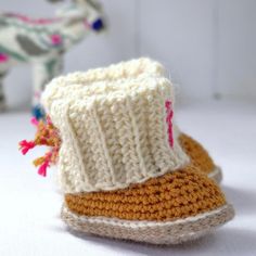 two knitted shoes sitting on top of a table next to a stuffed animal horse