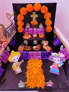 a decorated table with orange flowers and decorations on it's sides, in front of a black background