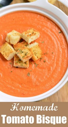 a white bowl filled with tomato biscuit soup and topped with croutons on top