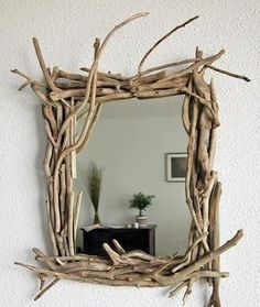 a mirror made out of driftwood is hanging on the wall next to a table