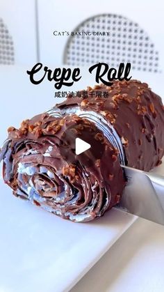 a knife cutting into a chocolate cake with the words crepe roll on it