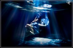 a woman is floating in the water with sunlight streaming through her