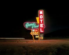 a motel sign lit up at night with the lights on and no one around it