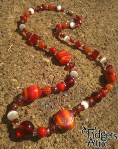 "The Red Cosmic necklace features an \"out-of-this-world\" mix of reds, oranges, and whites.  Made with a variety of red and white glass beads, orange stone, and a simple silver barrel clasp.  Measures about 24 inches in length." Cosmic Necklace, Red Beaded Necklace, Red Beaded Necklaces, Orange Stone, Necklace Red, Paper Beads, Red Bead, Etsy Jewelry, Jewelry Projects