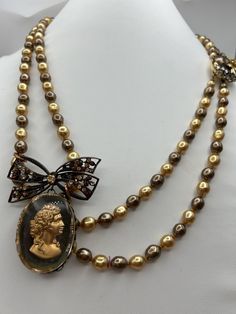 I designed and created this piece using:  1.Vintage Double strand bronze and gold pearls (likely faux but I have no idea); and  2. Vintage Cameo and bow brooch sourced in Newport RI.  Pendant Size: 2 1/4" x 2" Wearable Length: 19" 🌺ABOUT KIKIBLOOMS My one-of-a-kind designs are thoughtfully curated vintage and antique pieces that honor their past while highlighting their original beauty. As with most vintage pieces that have been preloved, there can be natural signs of aging and wear; please examine the photos carefully and feel free to ask questions. Gold Cameo Jewelry For Party, Vintage Gold Pearl Necklace For Evening, Handmade Gold Vintage Pearl Necklace, Handmade Vintage Gold Pearl Necklace, Bow Brooch, Newport Ri, Vintage Cameo, Be Natural, Curated Vintage