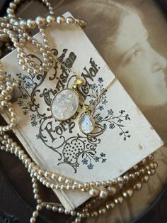 a close up of a necklace on a plate with pearls and a card in the background