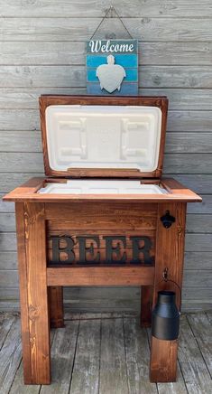 an old wooden cooler with the word beer on it and a welcome sign above it