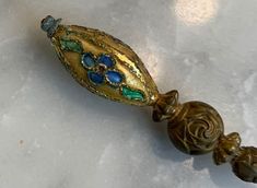 an ornate glass bead with blue, green and gold flowers on it's end