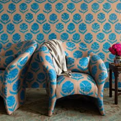 a blue and beige chair sitting next to a table with flowers on top of it