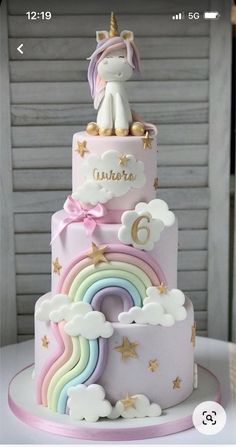 a three tiered cake decorated with unicorns and rainbows is on top of a table