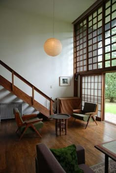 a living room filled with furniture next to a wooden stair case in front of a window