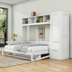 a white bed sitting in a bedroom next to a book shelf and window with lots of windows