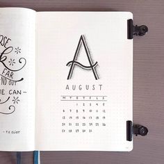 an open notebook with the word august written in black ink on it, next to a pen