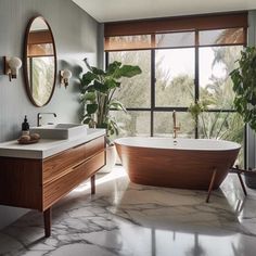 a bath tub sitting next to a large window in a bathroom under a round mirror