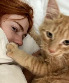 a woman laying in bed with a cat