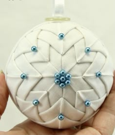 a hand holding a white ornament with blue beads