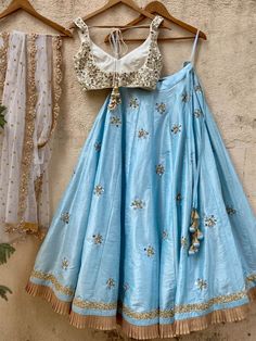 A three-piece Aqua Blue and Ivory Mirror Ruffle Lehenga Set from the Priti Sahni collection. This elegant raw silk aqua blue lehenga with mirror butti detail, sequin and ruffle border is paired with an ivory blouse in raw silk fabric with mirror, pearl and beads hand work embroidery. The lehenga has side hanging ball tassels to the waistline. This outfit is completed with an ivory tulle dupatta in net material with sequin work scalloped edging. Sea Blue Lehenga, Blue Silk Embellished Lehenga, Blue Raw Silk Traditional Wear With Mirror Work, Elegant Blue Choli With Gota Work, Blue Silk Choli With Mirror Work, Blue Raw Silk Dupatta With Mirror Work, Blue Raw Silk Sharara With Gota Work, Blue Dola Silk Lehenga With Mirror Work, Blue Raw Silk Sharara With Mirror Work