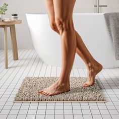 a woman's bare legs are shown in front of a bathtub and rug