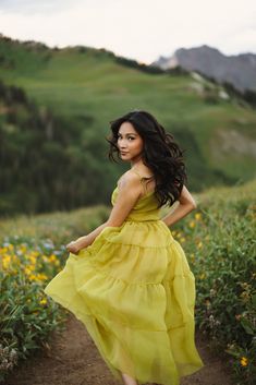 a woman in a yellow dress is walking down a path