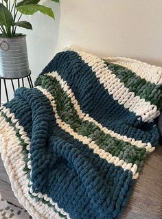 a crocheted blanket sitting on top of a couch next to a potted plant