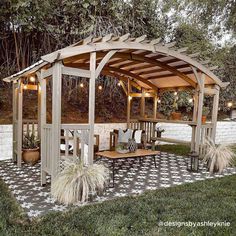 a wooden gazebo sitting on top of a lush green field