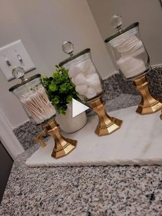 two glass jars filled with different types of items on top of a marble countertop