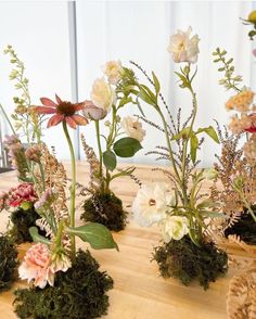 several vases filled with flowers on top of a wooden table