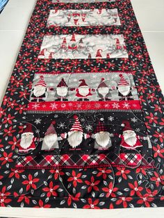 the table runner is decorated with red, white and black christmas themed items on it