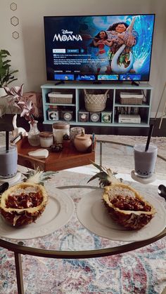 two pineapples are sitting on plates in front of a television with moan logo