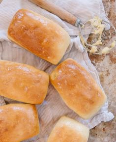 four loaves of bread sitting on top of a cloth next to a rolling pin