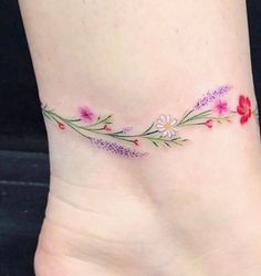 a woman's foot with flowers and leaves on the side, tattooing it