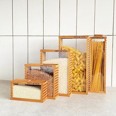 three wooden boxes filled with different types of pasta and other items in front of a tiled wall