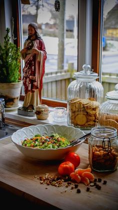 a wooden table topped with bowls filled with food next to glass containers full of food