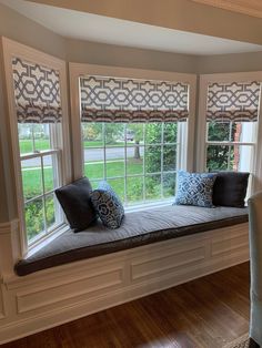 a window seat with pillows on it in the middle of a room that has wood floors